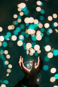 Midsection of person with illuminated lights at night