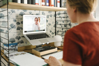 Businesswoman discussing with female colleague on video call through laptop at home