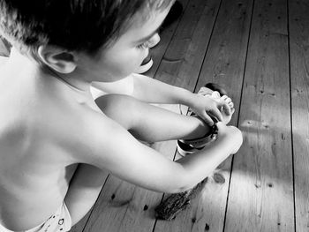 High angle view of boy sitting on wooden floor