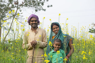 Full length of happy friends standing on field against plants