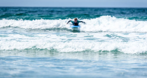 Woman surfing in sea against sky