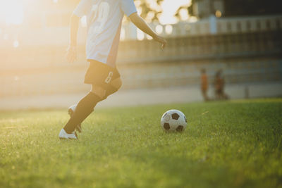 Low section of man playing soccer ball on grass