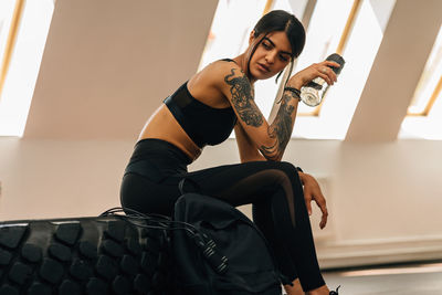 Young woman sitting on tire at gym