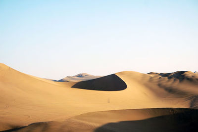 Sand dunes in desert against clear sky