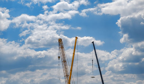Construction cranes in the blue sky with clouds