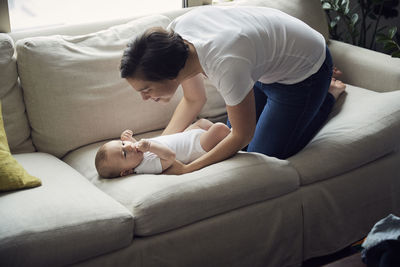 High angle view of happy mother laying son on sofa at home