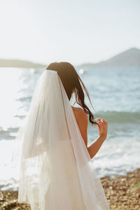 Rear view of bride standing at beach