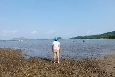 Rear view of man standing on beach against sky