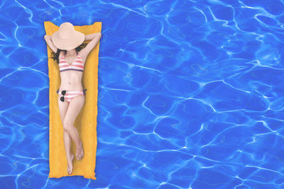 Woman relaxing on raft in swimming pool