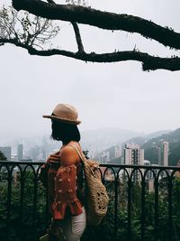 Rear view of man standing by railing against sky