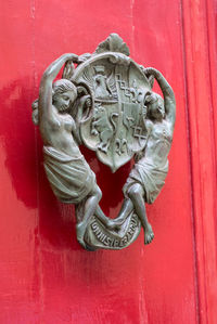 Close-up of statue against red door