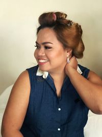 Portrait of smiling young woman looking away against wall