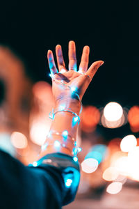 Close-up of human hand against illuminated lights