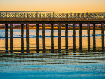 Bridge over sea against clear sky during sunset