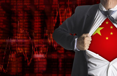 Midsection of businessman showing chinese flag below suit against chart