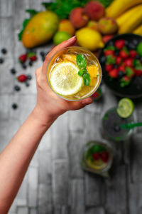 Cropped hand of woman holding fruit on table