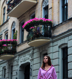 Portrait of woman standing against building in city