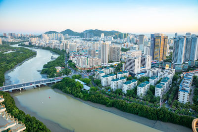 High angle view of city by river and buildings against sky