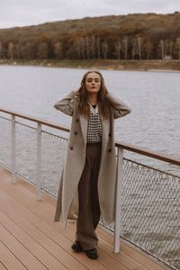 Young woman standing against lake
