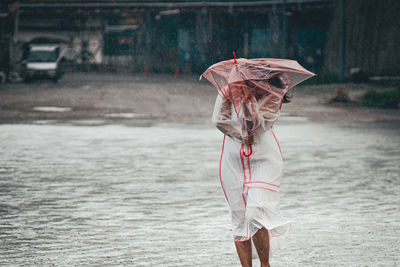 Young woman holding umbrella during rainy season