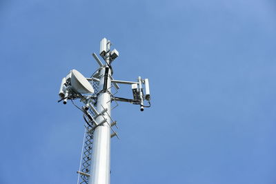 Low angle view of telephone pole against clear blue sky