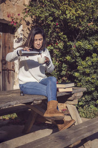 Beautiful latina woman pours a cup of coffee, in the countryside