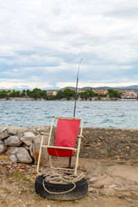 Deck chair on sea shore against sky