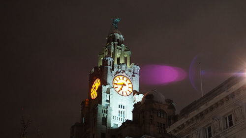 Low angle view of illuminated clock tower at night