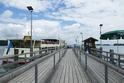 Ferry moored at harbor against cloudy sky