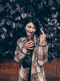 Smiling young woman holding ice cream standing outdoors