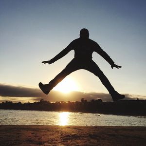 Silhouette man jumping against sky during sunset