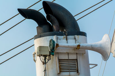 Low angle view of ship horn and smoke stack against clear sky