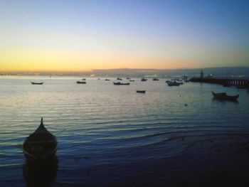 Boats in sea at sunset