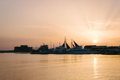 Silhouette boats moored at harbor against sky during sunset