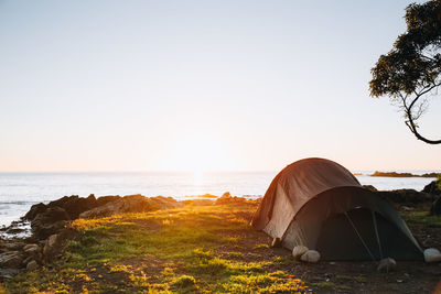 Tent on rock by sea against clear sky