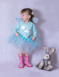 Cute little girl in fairy costume standing with stuffed toy on white background