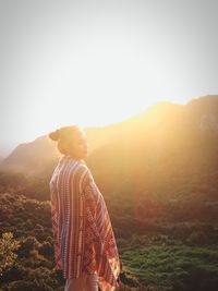 Woman standing against mountains during sunset