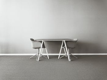 Empty chairs and table against wall at home