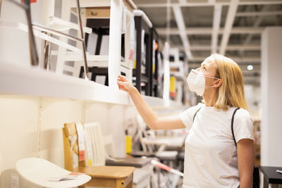 Side view of woman wearing mask standing at store