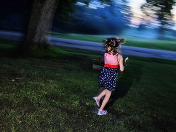 Blurred motion of girl playing on field at dusk