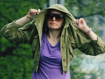 Portrait of young woman standing against plants