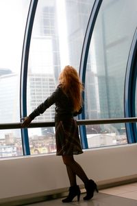 Side view of woman standing by railing in modern building