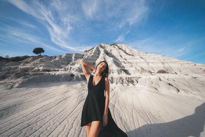 Young woman standing on mountain against sky