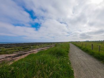 Road amidst field against sky