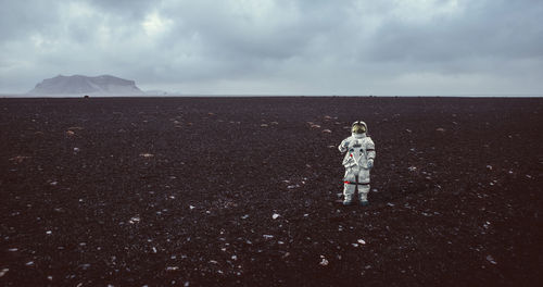 Full length of astronaut standing on field against sky