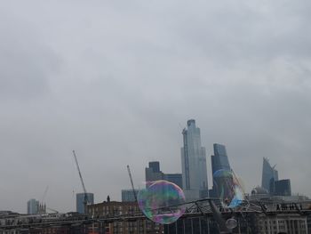 Low angle view of rainbow over buildings in city against sky