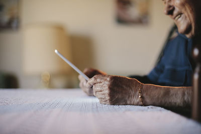 Cropped image of senior man holding tablet computer at table