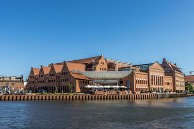 Buildings at waterfront against blue sky