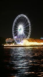 Illuminated ferris wheel against sky at night