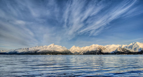 Scenic view of lake by snowcapped mountains against sky